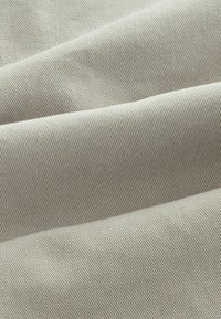Tejido gris claro con una superficie suave y ligeramente texturizada, que presenta un patrón de ribete diagonal. Adecuado para diversas aplicaciones textiles.