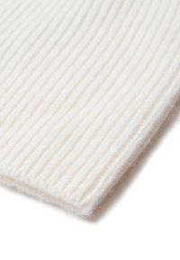 Tejido textil blanco acanalado con una textura suave y fibras visibles, doblado en la esquina, mostrando su estructura flexible y gruesa.