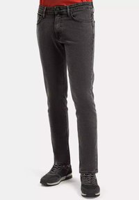 Ciemnoszare dżinsy w slim fit, klasyczny pięciokieszeniowy styl oraz subtelna, prana tekstura. Połączone z ciemnymi butami sportowymi.