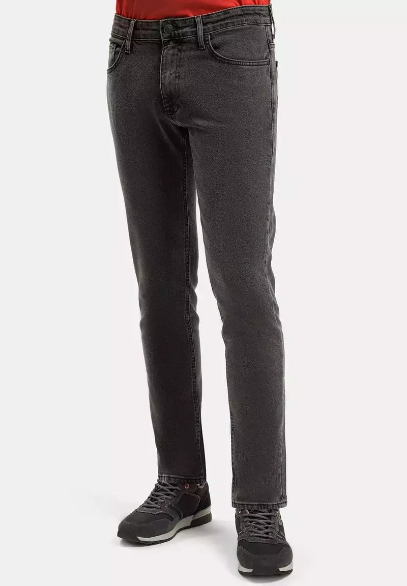 Ciemnoszare dżinsy w slim fit, klasyczny pięciokieszeniowy styl oraz subtelna, prana tekstura. Połączone z ciemnymi butami sportowymi.