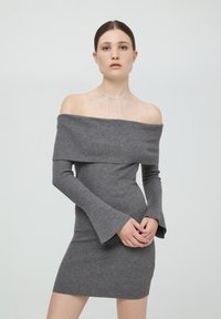 Abito grigio a spalle scoperte con maniche lunghe a campana, realizzato in un tessuto a maglia testurizzato. Presenta una silhouette aderente.