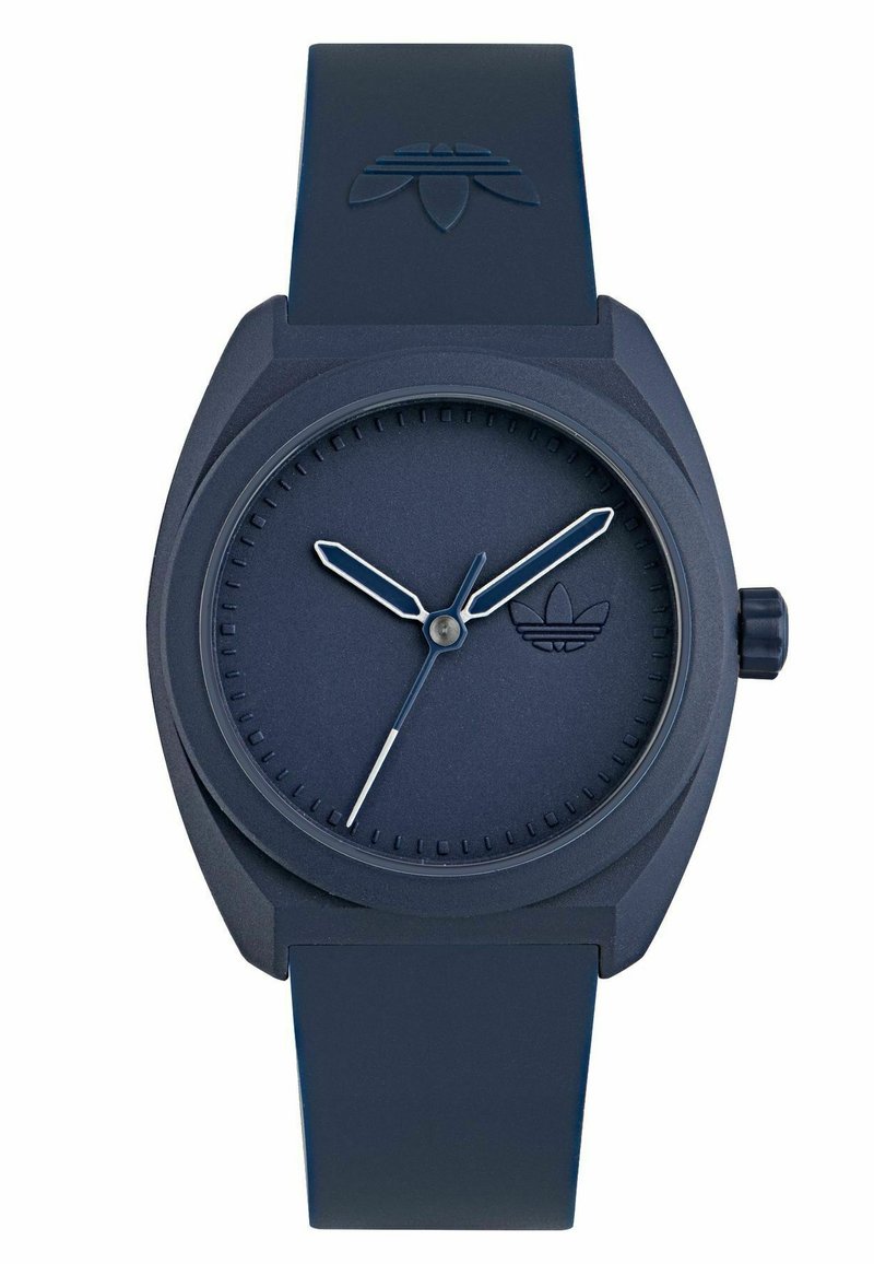 Tamsiai mėlynas silikono laikrodis su tekstūruotu dirželiu, minimalistiniu apvaliu ciferblatu ir sidabriniais valandų bei minučių rodyklėmis. Ciferblate yra mažas logotipas.