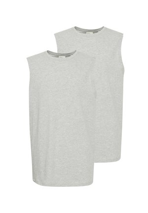 T-shirt sans manches gris clair, shorts en denim bleu avec des revers et des détails déchirés, chaussettes blanches et baskets noir et blanc.