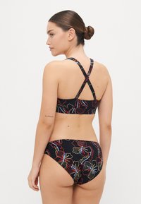 Black bikini set featuring floral patterns in red, yellow, and blue. Racerback design with cross straps and a high-cut bottom.
