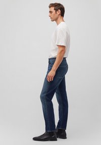 Dark blue denim jeans with a straight cut, worn with a plain white t-shirt and black ankle boots. Slim fit with five pockets and stitching details.