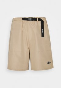 Short beige en tissu lisse, doté d'une ceinture noire ajustable, de deux poches avant et d'un patch logo noir sur le côté inférieur.