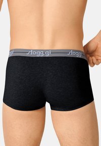 Musta puuvillatrunkit, joissa on harmaa elastinen vyötärönauha ja "sloggi"-logo. Materiaali on sileä ja istuva malli.