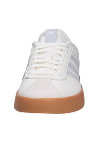 Zapatilla blanca de Adidas con rayas azul claro, cordones blancos y suela de goma color caramelo, vista frontal.