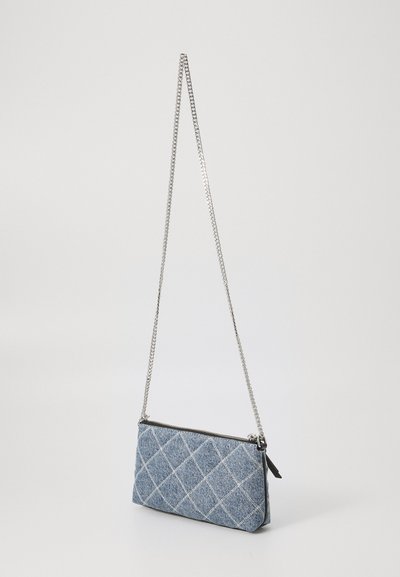 Bolsa de ombro em denim com padrão acolchoado, alça de corrente prateada e fecho com zíper. Forma retangular com detalhes de costura em contraste.