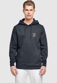 Mörkgrå hoodie i bomull med en framficka och dragsko huva. Dekorerad med en färgglad blommig grafik på bröstet.