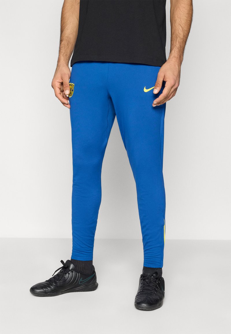 Blaue Sporthose aus glattem, dehnbarem Stoff mit gelbem Nike-Logo und Aufnähern. Eng anliegendes Design, kegelförmiger Schnitt, kontrastierende Seitenakzente.