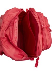 Punainen kangasreppu, jossa useita osastoja, mukaan lukien verkkotasku. Vetoketjusulkimet ja säädettävät olkahihnat näkyvissä.