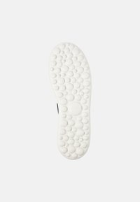 White rubber shoe sole with a textured, bubble-like pattern. Features a circular logo and size marking. Smooth edges, rounded shape.