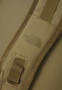 Olivgrön tygrem med texturerad väv, förstärkt sömnad och en formad logotypapplikation av The North Face. Justeras för ergonomisk passform.