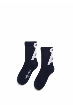 Paire de chaussettes crew noires avec un grand motif blanc en forme de "A" et le texte "AMED ANGELS EU 39-42" sur la zone du pied.