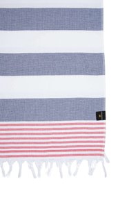 Cotton beach towel with alternating navy, white, and red stripes, featuring a fringed edge and a small tag in the corner.