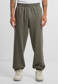 Gray jogger pants made of soft fabric, featuring an elastic waistband and relaxed fit tapering at the ankle. Worn with cream sneakers.