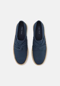 Zapatos espadrilles de lona azul marino con un diseño de nudo retorcido en la parte frontal, que cuentan con una suela de yute natural y una textura suave en toda la superficie.