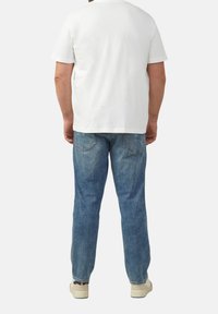 Witte katoenen t-shirt met korte mouwen, gecombineerd met blauwe spijkerbroek. De spijkerbroek heeft een klassiek vijf-pocket ontwerp en een vervaagde afwerking.