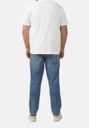 Witte katoenen t-shirt met korte mouwen, gecombineerd met blauwe spijkerbroek. De spijkerbroek heeft een klassiek vijf-pocket ontwerp en een vervaagde afwerking.