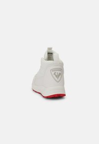 Scarpa sportiva bianca con tomaia testurizzata, suola rossa e accentuazione del logo grigia sul retro. Presenta una linguetta per una facile vestibilità.