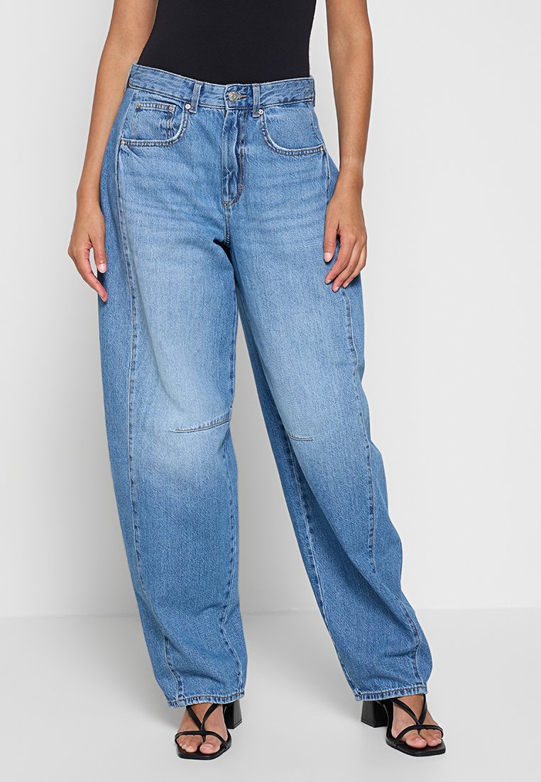 Jasnoniebieskie dżinsowe spodnie w szerokim kroju z wysokim stanem, pięcioma kieszeniami i widocznymi detalami przeszycia. Materiał wydaje się solidny i ma gładką fakturę.