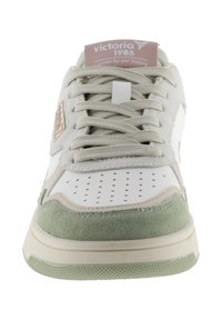 Sneaker bianca con accenti in suede verde, punta rotonda, design perforato, lacci piatti e un'etichetta con logo sulla linguetta. Suola in gomma testurizzata.