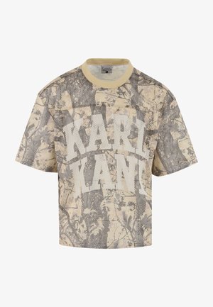Bézs színű, rövidített hálós póló terepmintával. Vastag fehér betűkkel nyomtatott "KARL KANI" felirattal. Rövid ujjú, kerek nyakkivágással.