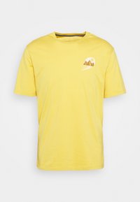 Camiseta amarilla de manga corta hecha de algodón con cuello redondo. Presenta una impresión gráfica de montañas y un sol en la parte izquierda del pecho.