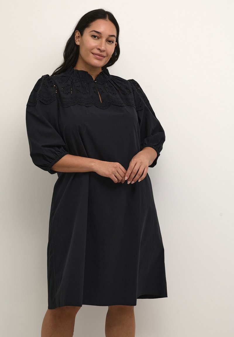 Vestido negro de manga corta y hasta la rodilla con un yugo de encaje texturizado y mangas abullonadas. Silueta simple, hecho de tela suave.