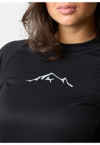 Black ribbed long-sleeve shirt featuring a white mountain silhouette logo on the chest. Soft texture with a fitted design.