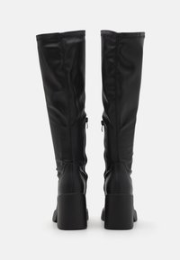 Botas altas hasta la rodilla de cuero sintético negro con un diseño elegante, textura suave, punta redonda y tacón cuadrado de bloque. Con cremalleras laterales.