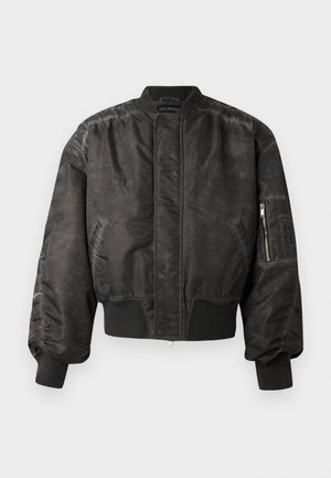 Casaco bomber preto com um acabamento suave e texturizado, punhos e bainha canelados, bolso com fecho de correr na manga e um design minimalista.