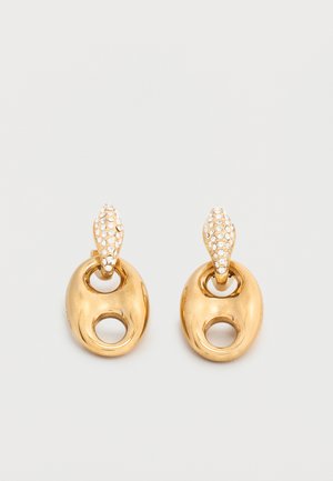 Goudkleurige ovale druppelvormige oorbellen met een kleine lusvormige uitsnede en met kristallen bestrooide druppelvormige studs op een neutrale achtergrond.