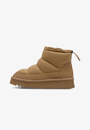 Beżowy ocieplany botek za kostkę z grubą, karbowaną podeszwą i pętelką z tyłu, zaprojektowany do noszenia na co dzień lub w chłodne dni.