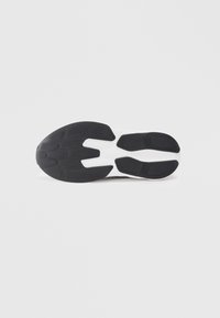 Semelle de chaussure de sport en noir et blanc avec une surface en caoutchouc texturée, présentant un design segmenté pour l'adhérence et la flexibilité.