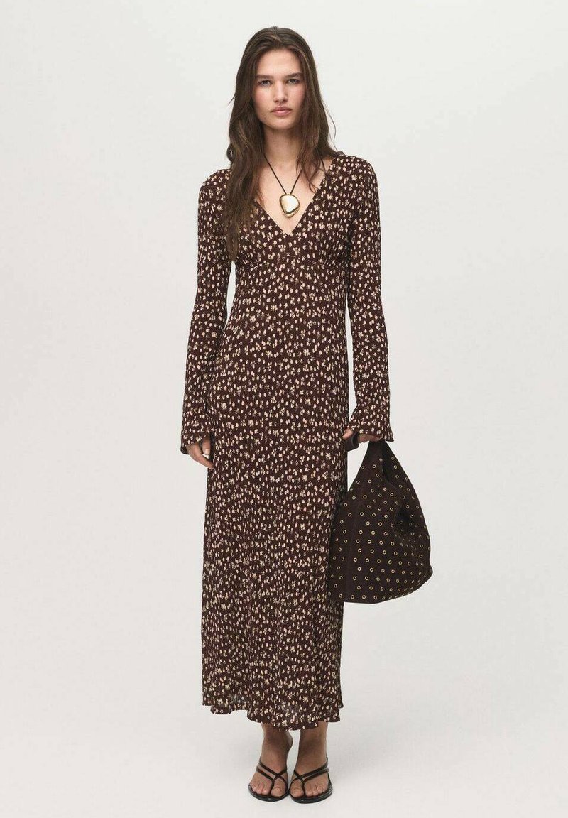 Robe maxi florale marron avec des manches longues, un décolleté en V et une silhouette fluide. Accordée avec un sac marron assorti avec des accents dorés.