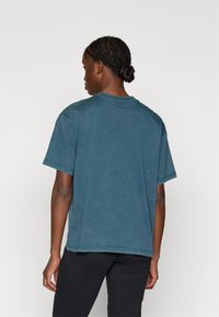 Ekologiškas medvilnės per didelis marškinėliai tamsiai žydros spalvos. Sukurta su apvaliu iškirpimu, trumpomis rankovėmis ir subtiliomis siuvimo detalėmis ant pečių.