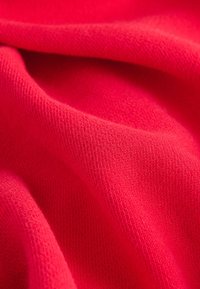 Flísová látka v živě růžové barvě, měkká textura s mírným elastickým efektem, ukazující hladký, rovnoměrný úplet bez viditelných ozdob.