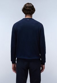 Marineblauer Pullover mit langen Ärmeln, gerippten Bündchen und Saum, strukturiertem Stoff und einem kleinen Logoschild hinten am Hals.