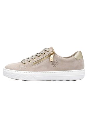 Beige suède sneaker met een witte rubberen zool, ronde neus, vetersluiting aan de voorkant en een gouden ritsdetail aan de zijkant. Zilveren oogjes.