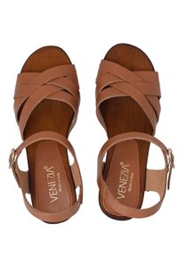 Hnědé kožené sandály s křížovým páskovým designem, otevřenými stranami a přezkovým uzávěrem. Dřevěné stélky s hladkým povrchem. Značka: VENEZIA.