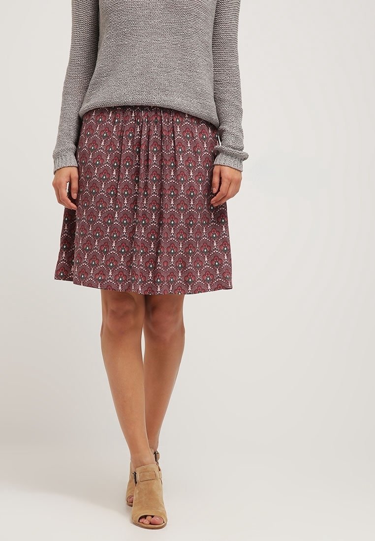Vínová sukně s potiskem a skládacím pasem, zdobená květinovými a paisley vzory. Spárována se šedým pleteným svetrem a béžovými sandály na otevřenou špičku.