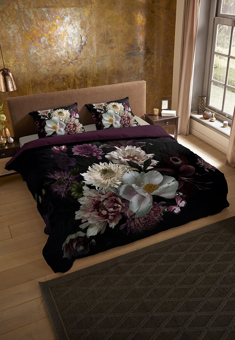 Bettwäsche-Set mit schwarz grundiertem Stoff, das große weiße, rosa und lila Blumen zeigt. Die passenden Kissen haben ein ähnliches florales Design.