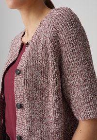 Kurzärmeliger Cardigan aus strukturiertem kastanienbraunem und cremefarbenem Garn, mit rundem Ausschnitt, Knopfleiste und lockerer Passform.