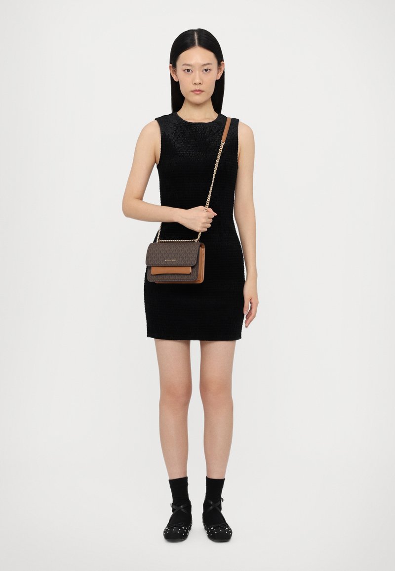 Black fitted dress with textured fabric, paired with a brown crossbody bag featuring a patterned flap and a gold chain strap.