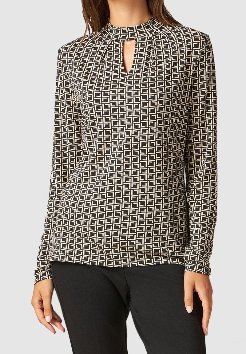 Long-sleeve top in black and cream with geometric pattern, featuring a high neckline and keyhole detail at the front. Soft fabric.