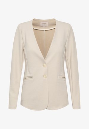 Blazer beige clair avec un profond décolleté en V, manches longues, deux poches avant et petits boutons crème. Texture de tissu lisse, coupe ajustée.