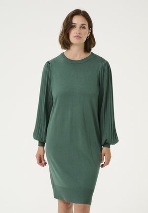 Robe en tricot verte avec de longues manches ballon plissées, un col rond et une jupe légèrement fuselée. Texture lisse avec des accents côtelés.