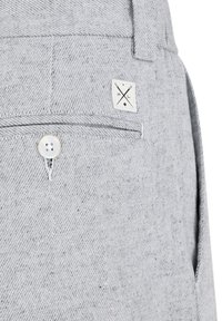 Jasnoszare dżinsowe szorty mają przednią kieszeń i widoczny biały guzik. Mała naszywka z logo jest wszyta nad kieszenią.